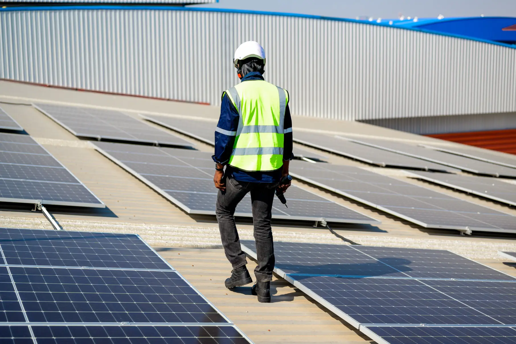 Engineer walking between solar panels on a business roof